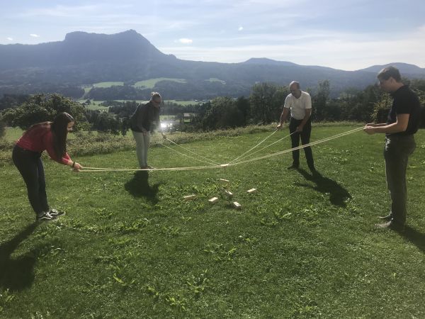 4 Teilnehmer in Gruppenübung auf einern Wiese